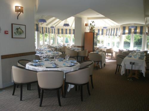une salle à manger avec des tables et des chaises blanches et des fenêtres dans l'établissement Hôtel Restaurant Le Rive Gauche, à Joigny