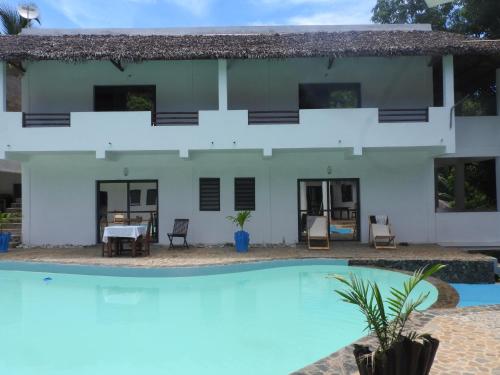 une villa avec une piscine en face de celle-ci dans l'établissement Auberge SAKATI'Art, à Nosy Be