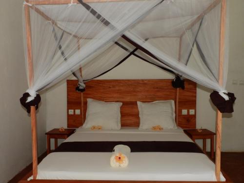 Schlafzimmer mit Himmelbett und weißen Vorhängen in der Unterkunft Auberge SAKATI'Art in Nosy Be
