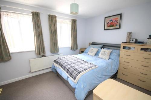 a bedroom with a bed and a dresser and windows at No1 Apartment House in Stainforth