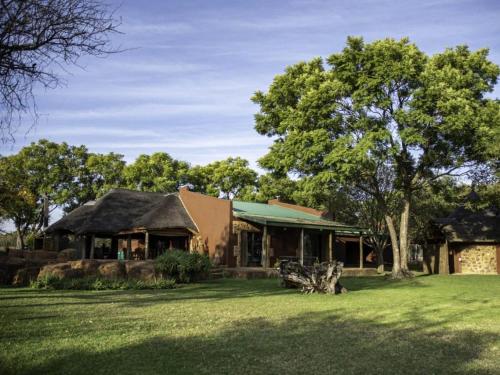 a building with a tree and a grass yard at Wild and Water Dinokeng in Dinokeng Game Reserve