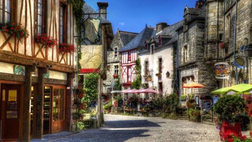 eine Straße mit Gebäuden und Sonnenschirmen in einer Stadt in der Unterkunft Le Moulin de Gueuzon in Rochefort-en-Terre