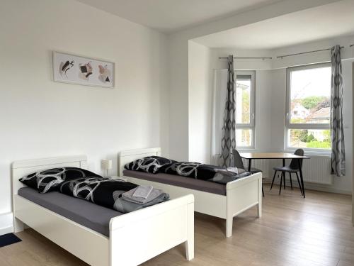 a bedroom with two beds and a table and a window at Zentrale Zweibettzimmer für Monteure I home2share in Bad Rothenfelde