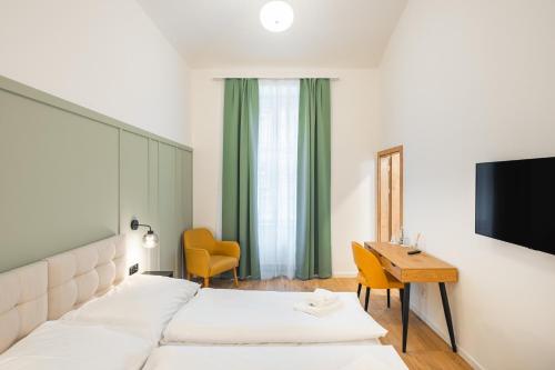 a bedroom with two beds and a desk and a television at Luma Terra Prague Hostel in Prague