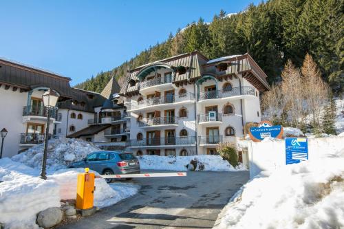 un grand bâtiment avec une voiture garée dans la neige dans l'établissement Résidence Le Cristal Apartments - Happy Rentals, à Chamonix-Mont-Blanc