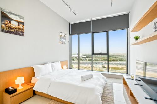 um quarto com uma cama, uma secretária e uma janela grande em Luxurious Studio - Free Poolgym em Dubai