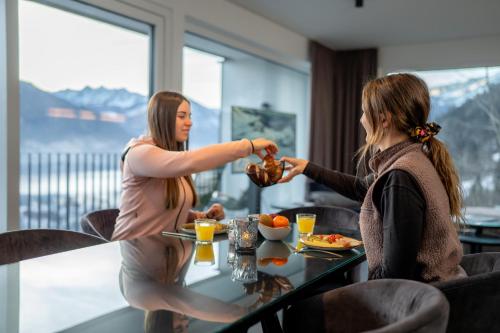 two women sitting at a table eating food at Nikolaus by AvenidA Panoramic Wellness Suites in Zell am See