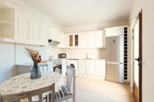 Casa Cauma Apartamento في بني الرزين: مطبخ أبيض مع طاولة وثلاجة