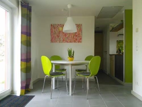 a dining room with a white table and green chairs at Villa Winzig in Beckerwitz