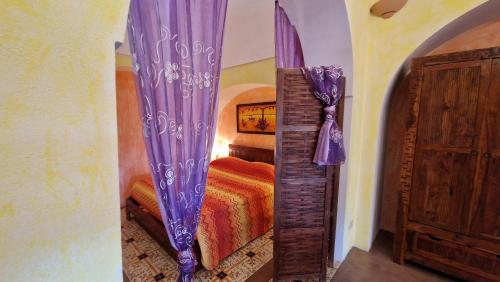 a bedroom with a bed with a purple curtain at I Dammusi di Punta Karace in Tracino