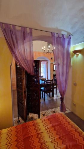 a bedroom with a bed with purple curtains and a dining room at I Dammusi di Punta Karace in Tracino