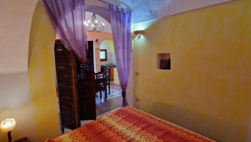 a bedroom with purple curtains and a dining room at I Dammusi di Punta Karace in Tracino