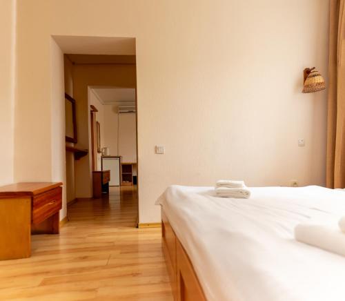 a bedroom with a white bed and a wooden floor at Asian Mountains in Bishkek