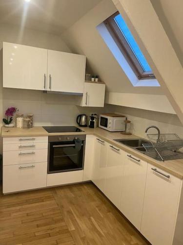 une cuisine avec des armoires blanches et une fenêtre dans l'établissement agréable, à Noisy-le-Sec