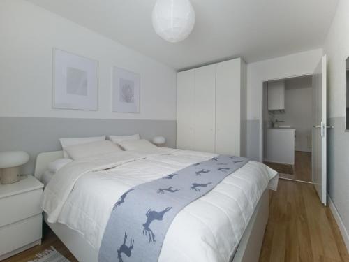 a white bedroom with a large bed with a blue blanket at Casa Bivio in Bivio