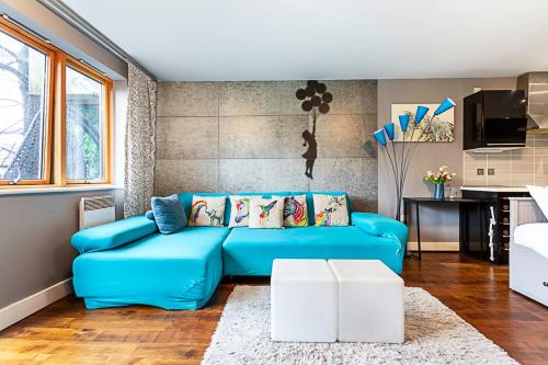 a living room with a blue couch and a kitchen at Modern 2-Bed Flat Bethnal Green in London