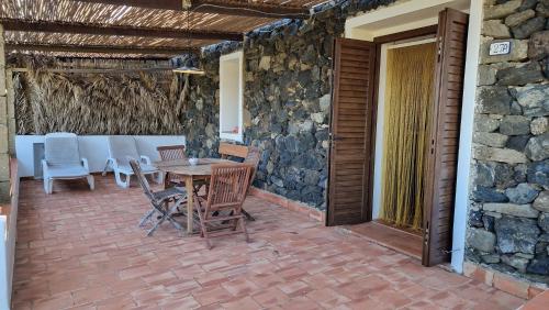 a patio with a table and chairs and a stone wall at I Dammusi di Punta Karace in Tracino