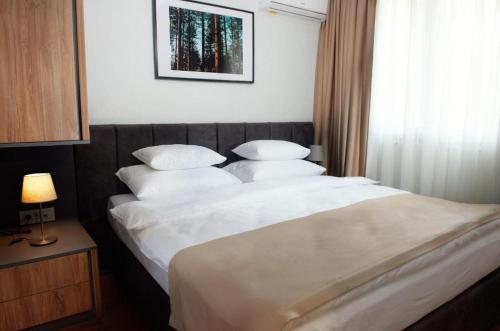 a bedroom with a large bed with white sheets and pillows at ZLATIBORSKO JEZERO 3 Lux@Spa in Zlatibor