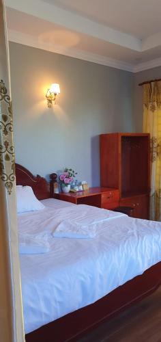 a bedroom with a large white bed and a dresser at Angkearsel GuestHouse in Kampot