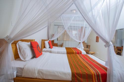 a bedroom with a bed with white drapes at SILVER OAKS HOTEL Boma in Fort Portal