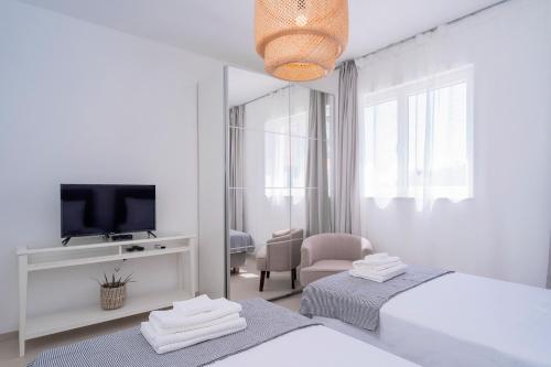 Habitación blanca con 2 camas y espejo. en Exclusive Seafront Suite with jacuzzi, en Zavala