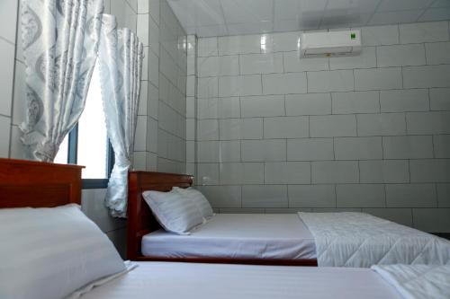 two beds in a small room with a window at Motel KIM PHÁT LUXURY - Núi Cấm in Phum Kokhlăng