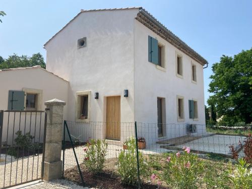 une maison blanche avec une clôture devant dans l'établissement LA MAISON DU PETIT JEU GRIGNAN, à Grignan