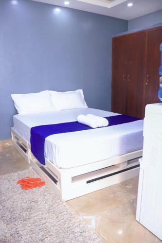 Cathys Studio Apartment في مومباسا: سرير ابيض في غرفة بجدار ازرق
