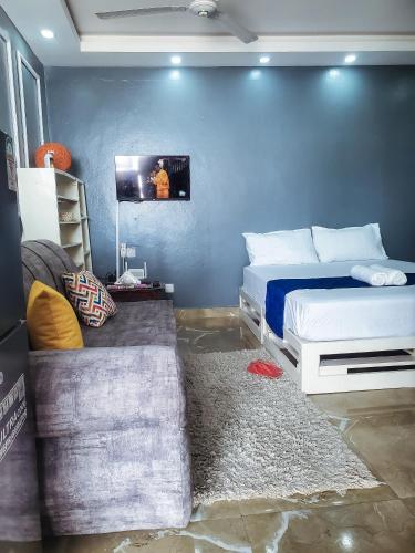 1 dormitorio con 2 camas y pared azul en Cathys Studio Apartment, en Mombasa