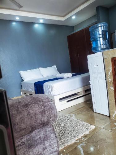 1 dormitorio pequeño con 1 cama y 1 sofá en Cathys Studio Apartment, en Mombasa