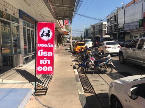 a sign on the side of a street with parked motorcycles at SP House RoiEd in Roi Et