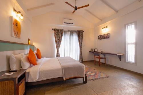 a bedroom with a bed and a desk and a window at Machaan Wilderness Lodge Nagarahole in Srimangala