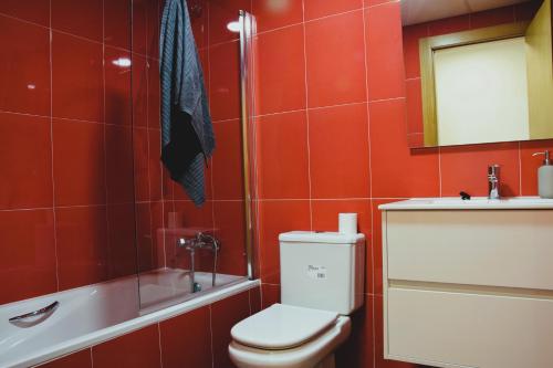 a red bathroom with a toilet and a sink at La Colegiata Suite in Lorca