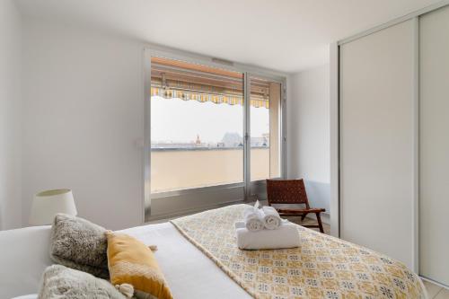 - une chambre avec une grande fenêtre et un lit avec une serviette dans l'établissement Le Ballast - Appt à Dinard avec balcons et garage, à Dinard