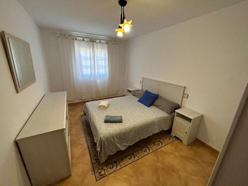 a small bedroom with a bed with blue pillows at Book Jet - Villa Vacacional libertad Pajara 