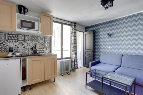 a living room with a blue couch and a kitchen at 129 Suite Haïm - Superbe Appartement à Paris. in Paris