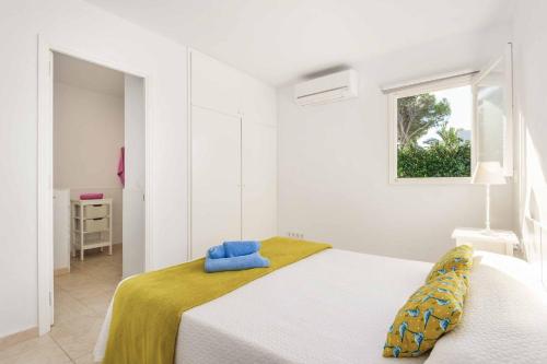a white bedroom with a bed and a window at Villa Tia Dora in Cala en Blanes