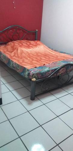 a bed with an orange comforter sitting on a tiled floor at SP House RoiEd in Roi Et