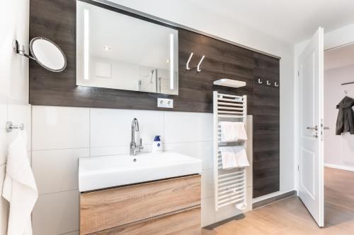 ein Badezimmer mit einem weißen Waschbecken und einem Spiegel in der Unterkunft Seegarten Appartements Büsum in Büsum