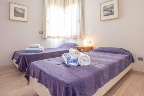 2 camas en una habitación con sábanas y toallas púrpuras en Villa Vista Alegre, en Palafrugell