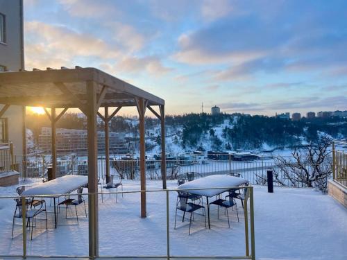 a covered deck with tables and chairs in the snow at Newly built bright apartment, close to everything. in Nacka