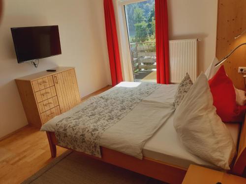 a bedroom with a bed with a television and a window at Apartmenthaus AMELIE in Lunz am See