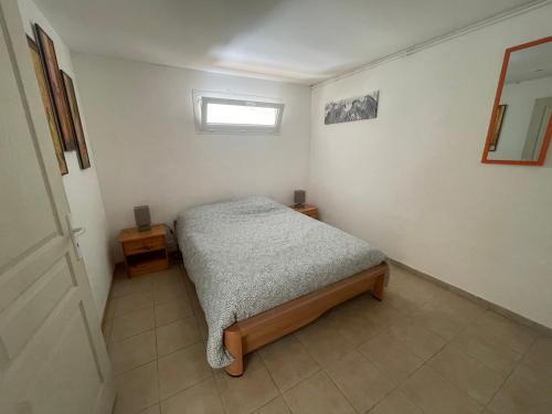 um pequeno quarto com uma cama e uma janela em Les Platanes - Rambrandt Rez de Jardin em Lamalou-les-Bains