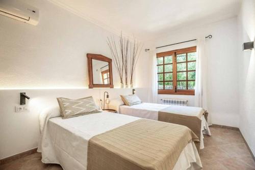 twee bedden in een kamer met een spiegel en een raam bij Villa Garrigo in Pollença