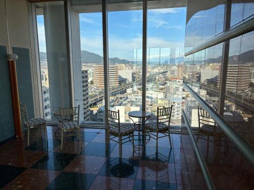 a table and chairs in a room with a view of a city at Chateraise Hotel Nagano in Nagano