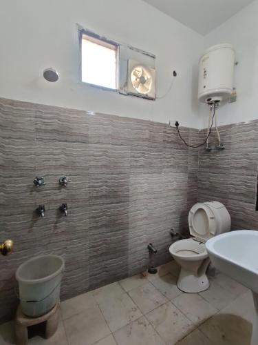ein Bad mit einem WC, einem Waschbecken und einem Fenster in der Unterkunft Hotel Parbhat Palace in Katra