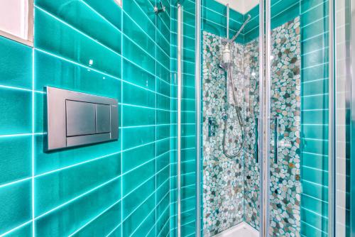 a blue tiled bathroom with a shower and a television at Trastevere, raffinato e silenzioso angolo in Rome