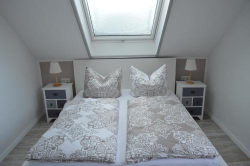 um quarto com uma cama com almofadas e uma janela em Apartment unterhalb der Burg Hanstein em Bornhagen