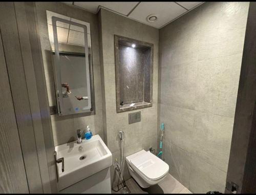 a bathroom with a sink and a toilet and a mirror at Skystay in Greater Noida