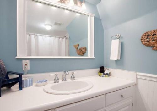 ein Badezimmer mit einem weißen Waschbecken und einem Spiegel in der Unterkunft Spring Sale 4BR Home w heated pool 2 min to beach in Destin